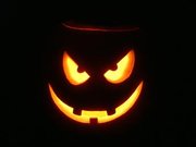 A jack-o'-lantern in the dark with a candle.