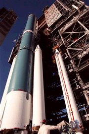 NASA Image of the final solid rocket booster (right) being mated to a Delta II rocket (blue). Two boosters (white) can be seen already attached.