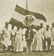 King Aweida standing in the middle before Germany's realm flag.