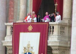 With a tapestry bearing the coat of arms of John Paul II hanging over the balcony, Benedict XVI is introduced to the crowd gathered in Saint Peter's Square.