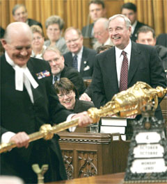 Canadian Sergeant-at-arms Gus Cloutier holding the  to open a sitting of the  with   in background (/)