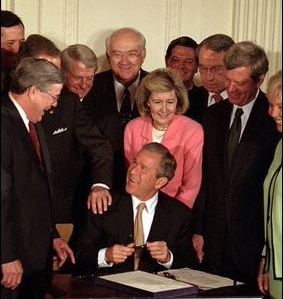 U.S. President  signs a bill into law at a public ceremony. As Head of State, the President's signature is required on all laws absent a  of congress.