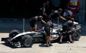 Members of the McLaren Formula One team push driver 's car into the garage during qualifying for the  at  in 2004