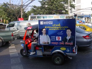 A Bangkok tuk-tuk sporting election advertising placards