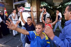 Photos of these Palestinian children were widely circulated shortly after the September 11 terrorist attacks. Allegedly, they are celebrating the attacks. German media analyzing the whole film highlighted that the surrounding area is relatively quiet, that the people celebrating only appear briefly and then quickly disappear, and that a single person in a white T-shirt (shown here in the background) appears to have incited the children. (Fair use of AP photo)