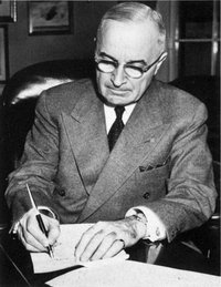 President Truman signing a proclamation declaring a national emergency that initiates U.S. involvement in the Korean War.