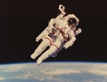 Bruce McCandless demonstrates the MMU floating in space above a clouded Earth. (NASA)