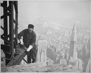 A worker helps raise the  25 floors higher than the  (seen to the right), completed just one year before, .