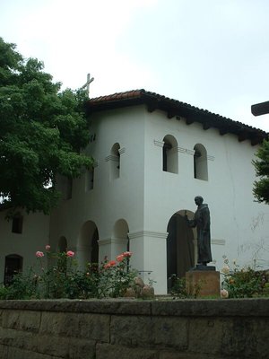 The entrance lobby and belfry of the Mission San Lus Obispo de Tolosa in  . A statue of Fray  stands outside the church.