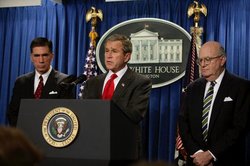 President Bush holds a press briefing at the White House on Friday, Feb. 6, 2004, announcing the formation of the commission. He is flanked by commission co-chairs Senator Charles Robb (left) and Judge Laurence Silberman (right).