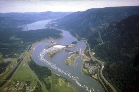 Aerial view of spillway flanked by powerhouses, Bonneville Lock (near right) and Lake Bonneville beyond