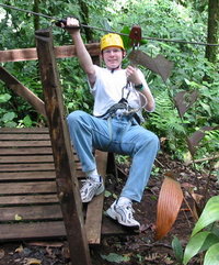 This rider prepares to descend to the right with  fastened to a pulley by two ropes.  In his right hand is a glove specially designed for controlling speed on a zip-line.